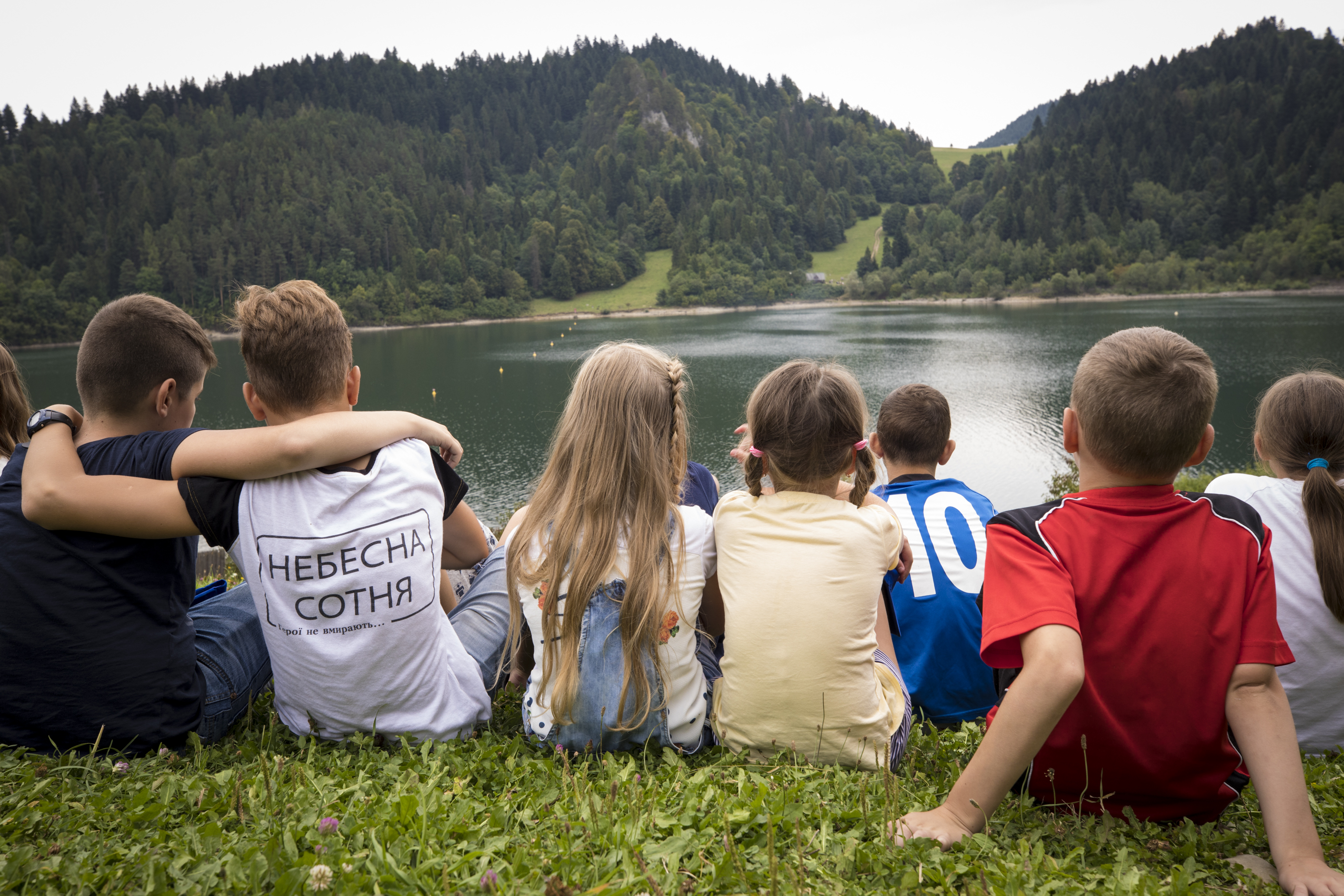 Children sit by a lake in Poland. All the children have lost parents or had parents severely injured in the conflict in Ukraine.